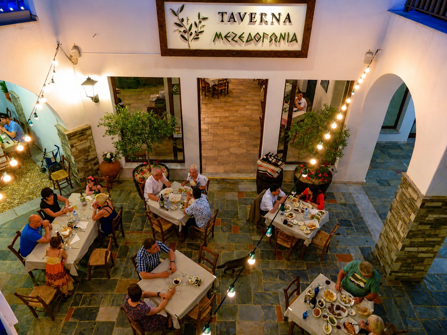 The courtyard of Mezedogonia Taverna at dusk, tables under string lights