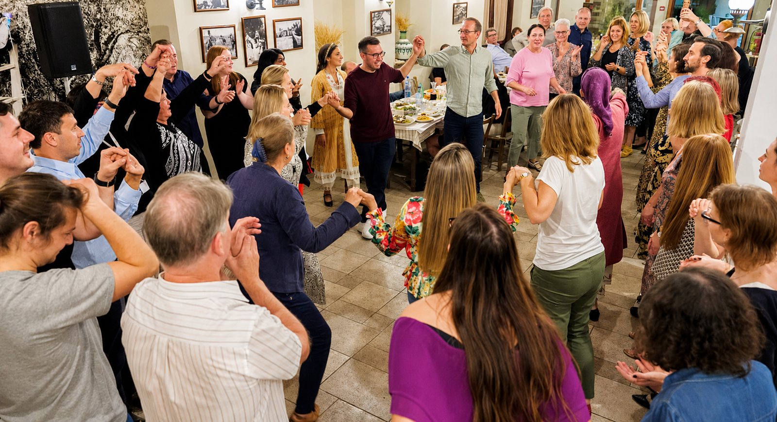 Guests holding hands in a circle dance inside the taverna